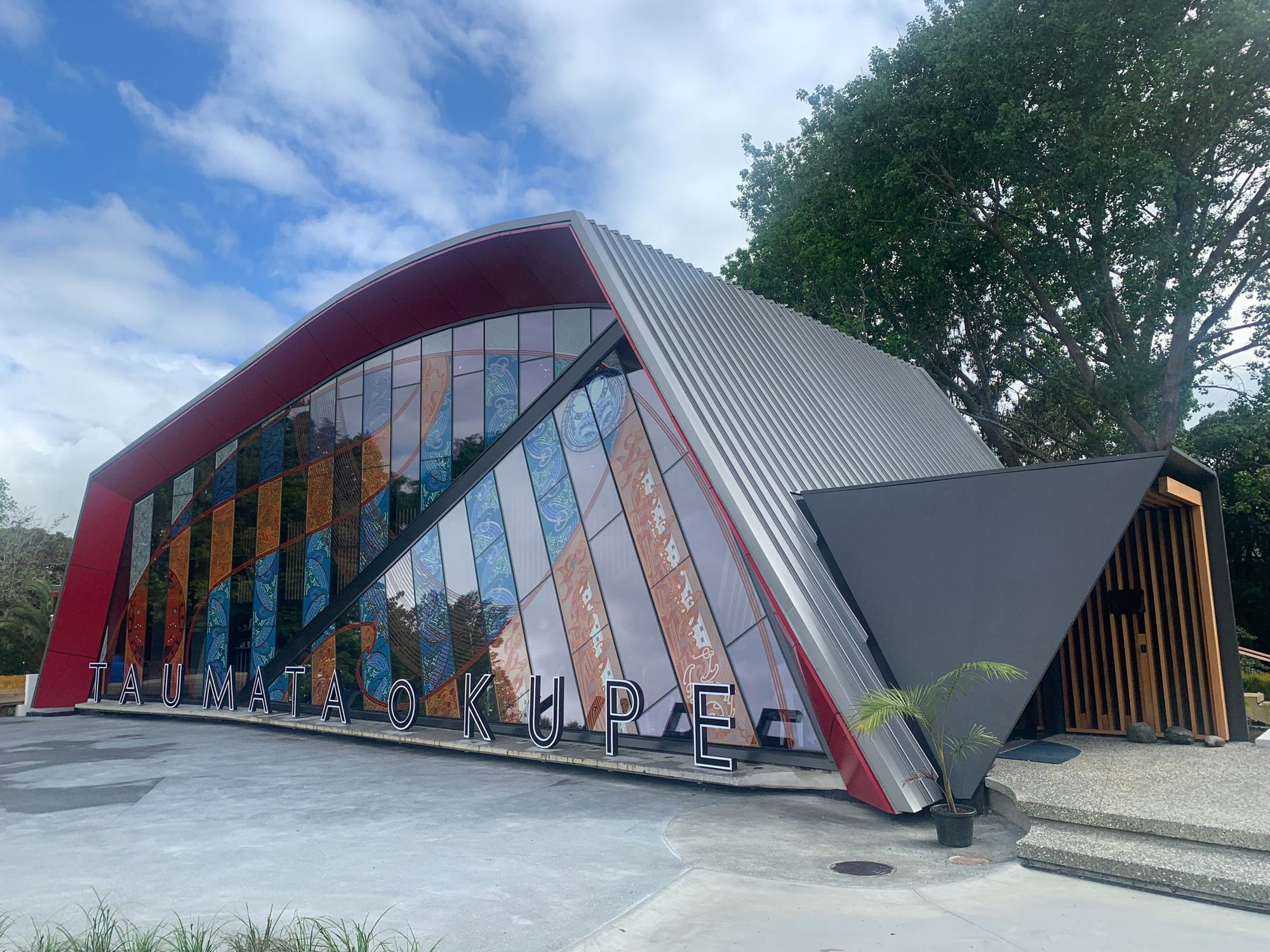Taumata o Kupe at dusk, red sculpted frame over a glazed façade